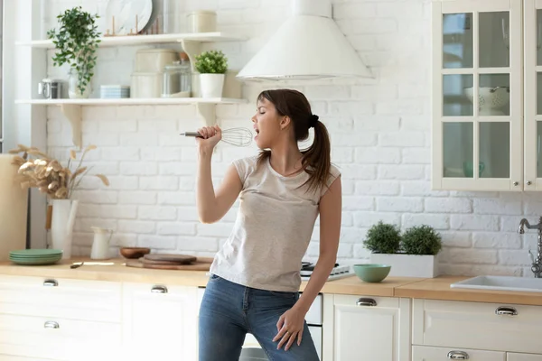 Zorgeloos jong vrouwelijk zingen in de keuken — Stockfoto