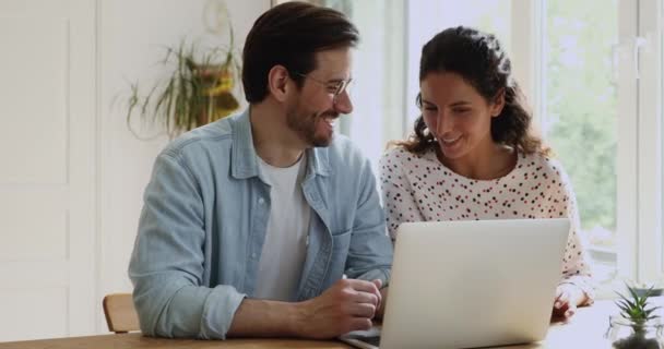 Paar zitten aan het bureau met behulp van laptop genieten van online winkelen samen — Stockvideo