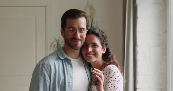 Счастливая пара обнимается показывая связку ключей из нового дома — стоковое видео
