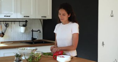Kadın mutfakta duruyor ve sağlıklı vitamin yaz salatası hazırlıyor.