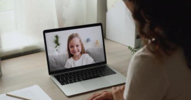 Çocuk video ile konuşuyor, dizüstü bilgisayar kadın omzunun üstünden bakıyor.