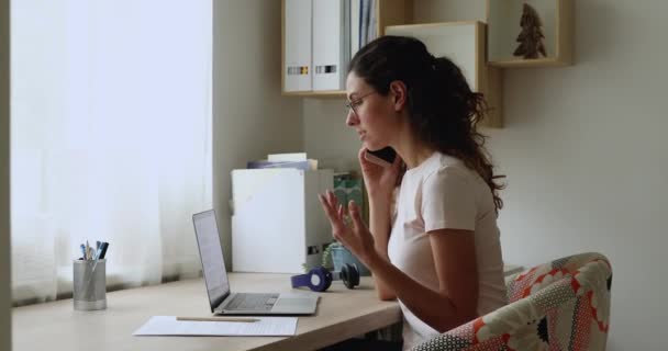 La donna d'affari guarda lo schermo del computer portatile tiene il cellulare che parla con il cliente — Video Stock