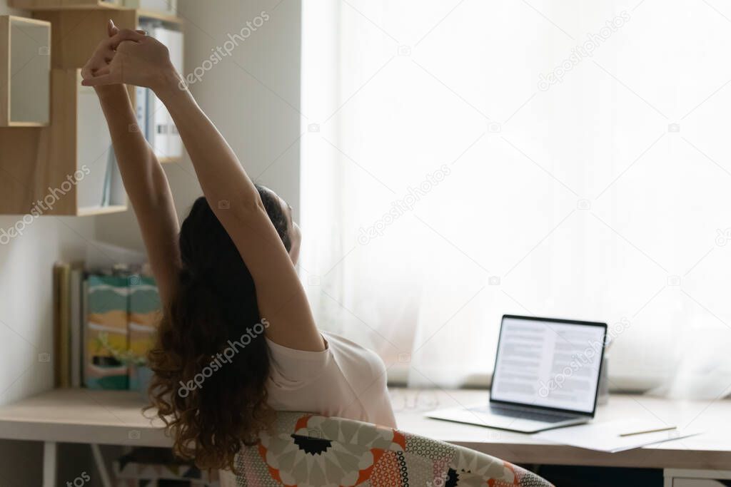 Young woman stretch in chair working on laptop