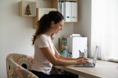 Gülümseyen kadın evde bilgisayarla çalışıyor.