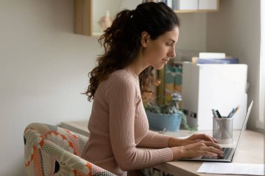 Genç beyaz kadın evden dizüstü bilgisayarla çalışıyor.