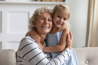 Mutlu yaşlı büyükanne kucağında küçük bir anaokulu torunu tutuyor.