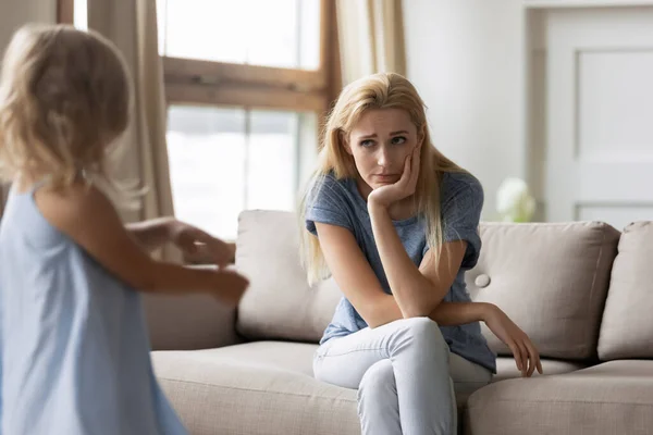 Distressed mom with pity face listening to capricious little daughter — Stock Photo, Image