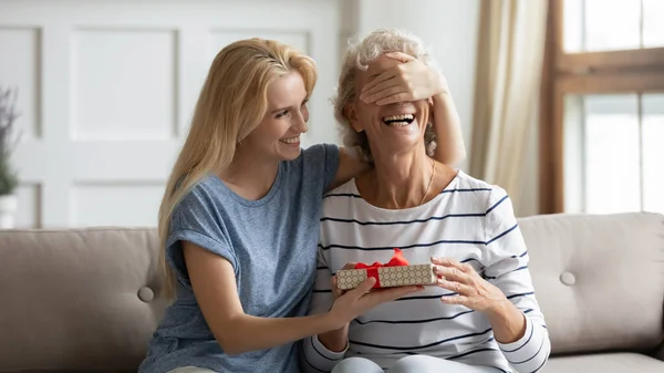 Lachen volwassen dochter feliciteert volwassen moeder geven haar verjaardag verrassing — Stockfoto