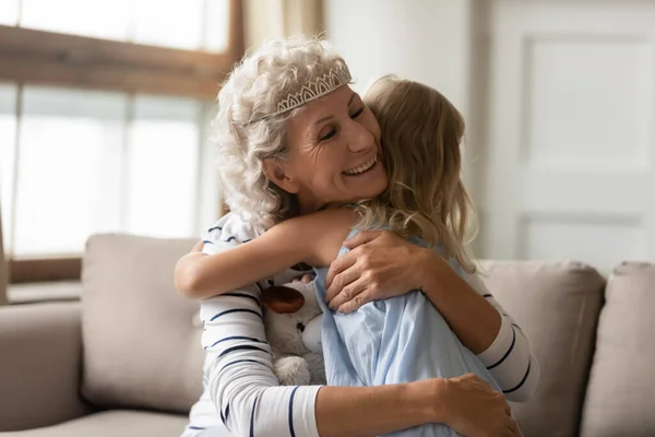 Szeretetteljes nagymama visel diadem ősz haj ölelés kis unokája — Stock Fotó