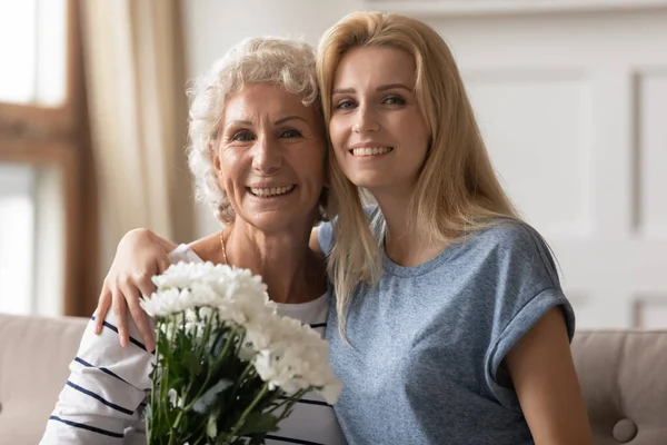 Sonriente anciana jubilada profesora recibiendo flores de ex estudiante —  Fotos de Stock