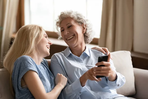 Happy aged and young females laughing at photo on phone