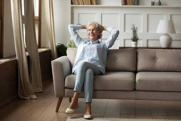 Happy senior woman resting on cozy sofa at living room — Stock Photo, Image