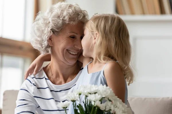 Cariñosa atenta nieta felicitando feliz madura abuelita con cumpleaños —  Fotos de Stock