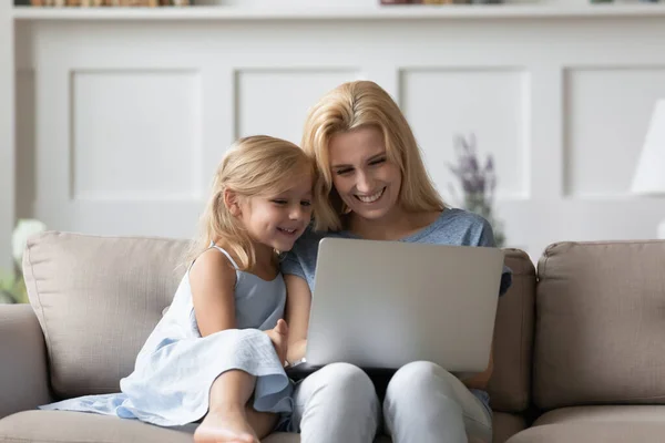 Millennial mor spelar spel på laptop med glad förskola dotter — Stockfoto