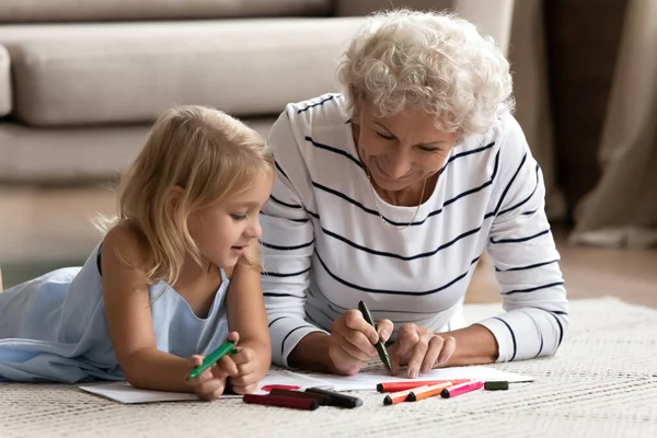 Yetişkin bir büyükanneye ilgi duyan bir torun anaokulu öğrencisine eskizler çizdirmeyi öğretiyorum. — Stok fotoğraf
