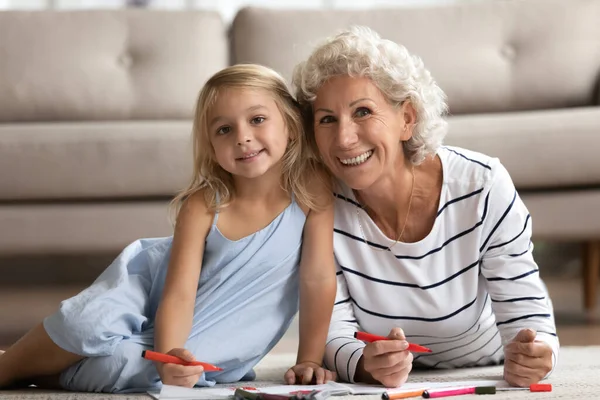 Grand-mère aînée et petite fille dessinant des images sur sol chauffé — Photo