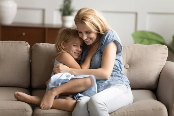 Hija pequeña y mami joven abrazándose en el sofá —  Fotos de Stock