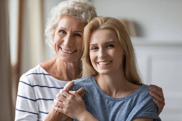 Heureuse enseignante âgée tendre embrassant une jeune ancienne élève féminine — Photo