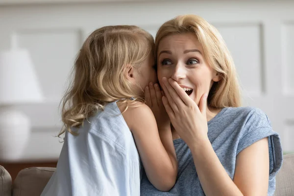 Freche Vorschulmädchen flüstern Witz auf erstaunten erwachsenen Schwester Ohr — Stockfoto