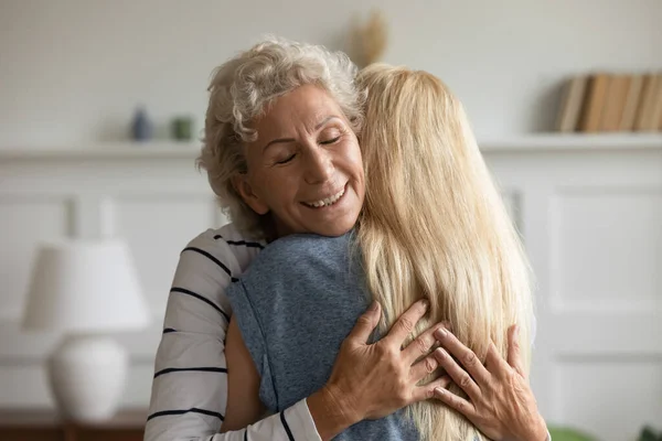 Feliz mamá jubilada disfrutando de los abrazos de la amada hija adulta — Foto de Stock