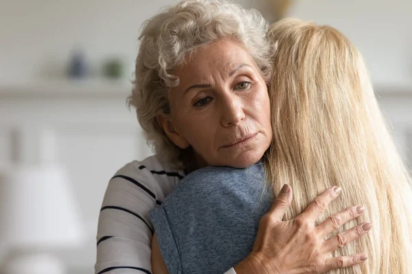 Mère âgée bienveillante embrassant sa fille adulte avec compassion dans les yeux — Photo