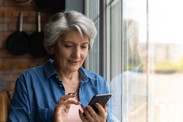 Modern mature woman use smartphone gadget texting