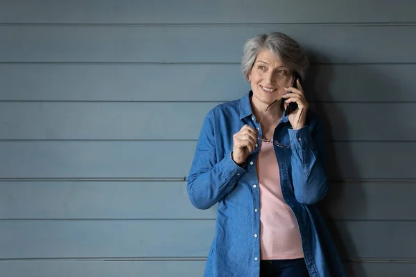 Sorridente donna matura parlare sul gadget del cellulare pensando — Foto Stock