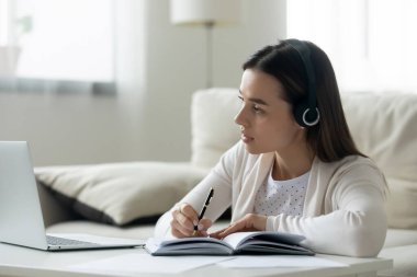 Milenyum dişisi kulaklıklarıyla evden internet üzerinden çalışıyor.