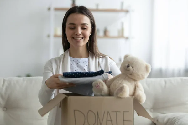 Freundliche junge Frau sammelt Spendenbox mit Kleidung — Stockfoto