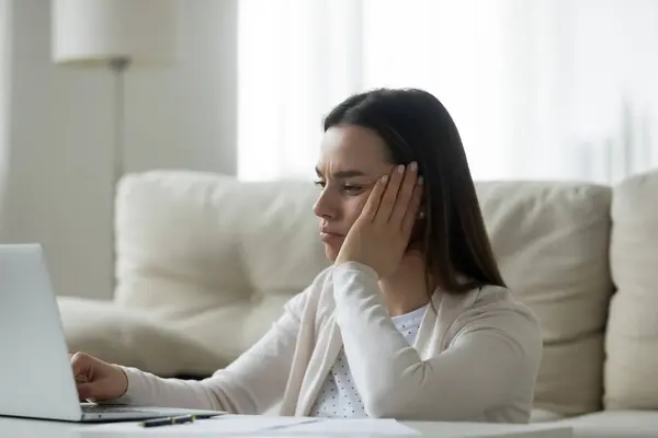 Mujer joven infeliz se siente aburrido de trabajar en el ordenador portátil —  Fotos de Stock