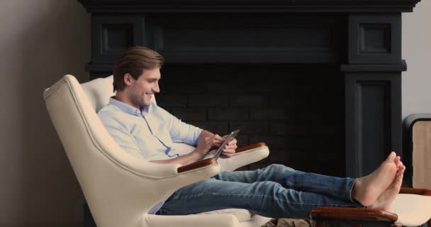 Mężczyzna osiadł w skórzanym fotelu odpoczywając z tabletem — Wideo stockowe