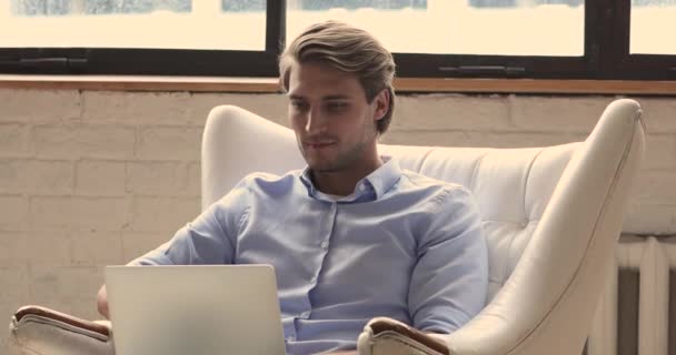 男人坐在扶手椅上使用笔记本电脑阅读邮件感到快乐 — 图库视频影像