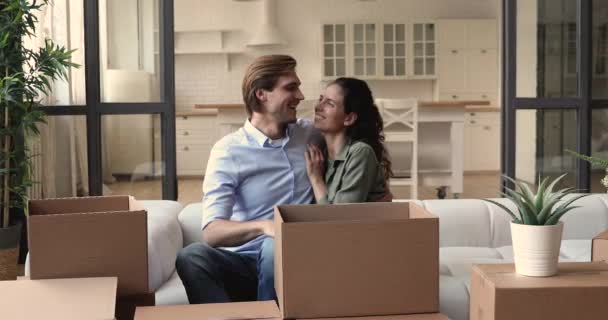 Пара сидят на диване рядом с картонными коробками в день переселения — стоковое видео