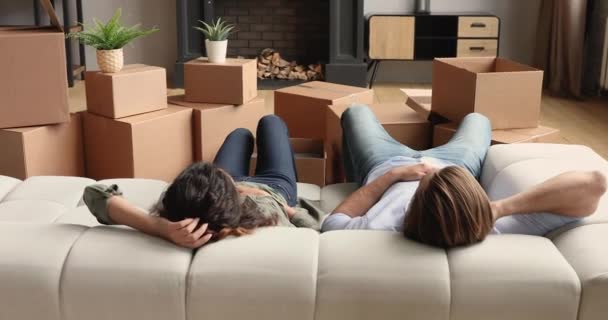 Pár odpočinku na gauči v blízkosti hromady zabalených krabic — Stock video