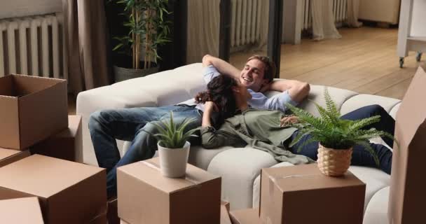 Супруги отдыхают на диване в день переселения в новом доме — стоковое видео