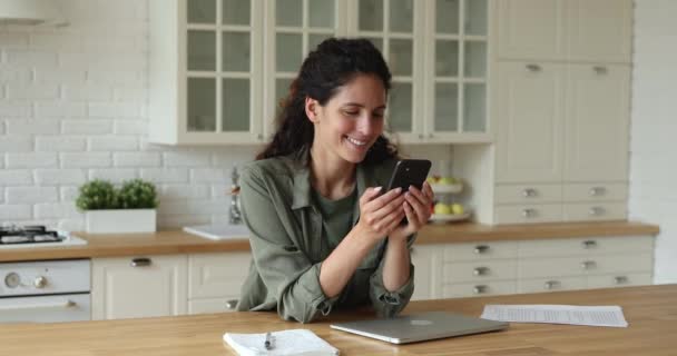 Mujer de pie en la cocina utilizando Internet en el teléfono inteligente — Vídeo de stock