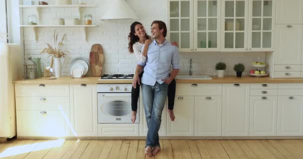 Breed volledig uitzicht gelukkig paar praten in moderne keuken — Stockvideo