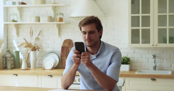 Guy κρατώντας smartphone κάνει την αγορά σε ιστοσελίδες ηλεκτρονικού εμπορίου από το σπίτι — Αρχείο Βίντεο
