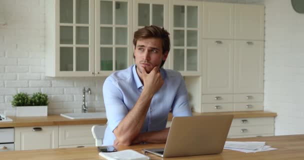 Geschäftsmann sitzt in Küche auf der Suche nach einer Lösung, während er aus der Ferne arbeitet — Stockvideo