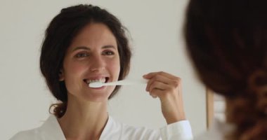 Dişlerini fırçalarken aynaya bakan çekici bir kadın.