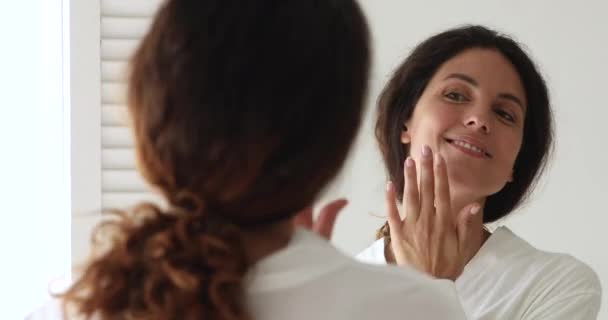 35s mujer mira en el espejo admira saludable impecable piel de la cara — Vídeos de Stock