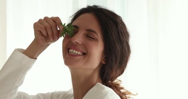 35 'lik kadın elinde yeşil maydanoz yaprağı kameraya bakıp gülümsüyor. — Stok video