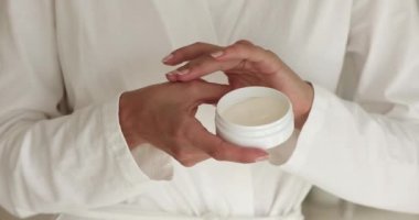 Bornozlu kadın cilt yakından görüntüsüne el kremi sür.