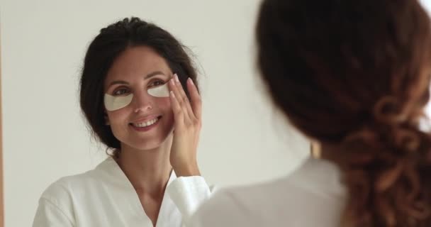 Mujer aplicar debajo de los ojos parches hidratantes tacto cara se siente feliz — Vídeo de stock