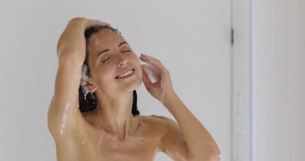 シャワーの下に立つ美しい女性は彼女の髪を洗う — ストック動画