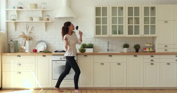 Домохозяйка держит ковш, как микрофон танцует пение во время подготовки ужина — стоковое видео