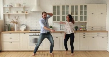 Mutlu çift evcil mutfakta dans ederken enerjik müzik dinliyor.