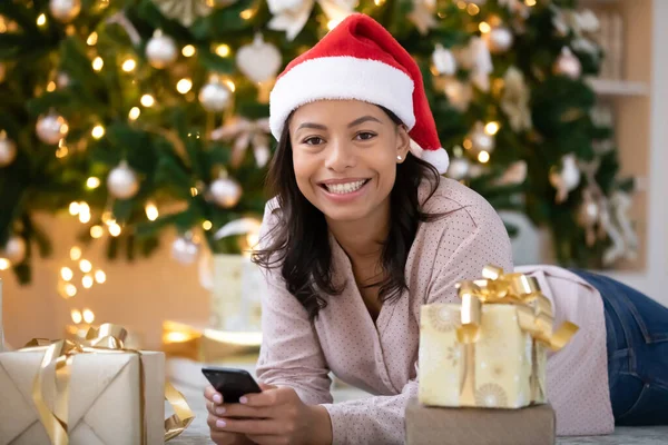 Leende afrikansk amerikansk kvinna sms jul hälsning på mobiltelefon — Stockfoto