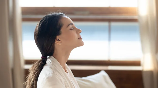 Pretty young girl sitting on sofa indoors relishing beautiful morning — Stock Photo, Image