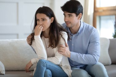 Koca, ağlayan bir kadının omuzlarını kucaklıyor. Karısının barışmayı teklif etmesi.